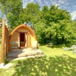 Pelouse avec cabane en bois et deux chaises longues du Camping-Hotel de Plein Air Les 2 Bois