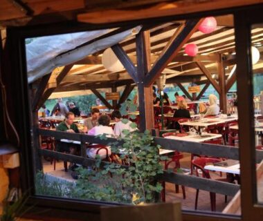 Terrasse couverte avec tables et convives au Camping-Hotel de Plein Air Les 2 Bois