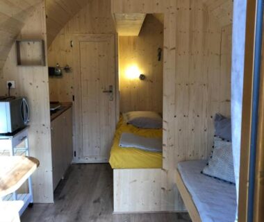 Intérieur d'un hébergement en bois avec coin nuit et kitchenette au Camping-Hotel de Plein Air Les 2 Bois