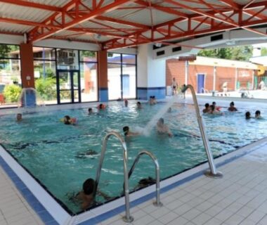 Piscine couverte avec jets d'eau et baigneurs au Camping Hurongues