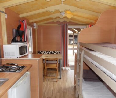Intérieur du mobil home avec kitchenette et lits superposés au Camping Insolite Le Haut Village