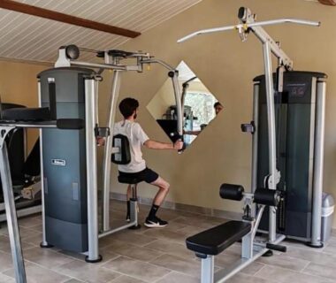 Salle de fitness intérieure avec appareils et miroir au Camping Kévano Plage