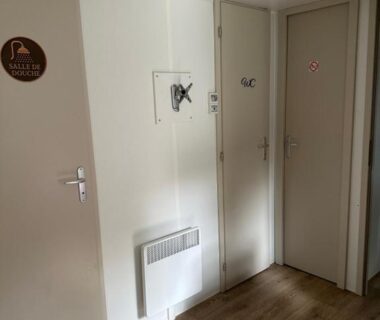 Couloir intérieur avec portes et sol stratifié au Camping L Eden Road