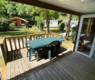 Terrasse en bois avec table et chaises donnant sur le jardin au Camping L Eden Road