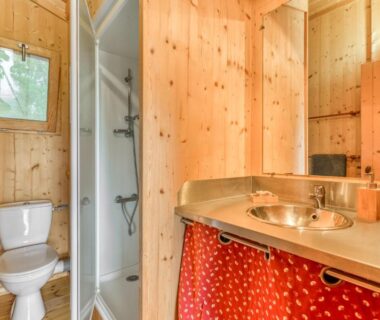 Salle de bains en bois avec douche et toilettes au camping LA SERRE