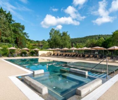 Piscine extérieure avec bains à remous transats et parasols au Camping LA SERRE