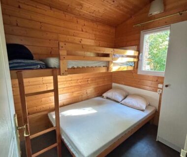 Intérieur cabine en bois avec lits superposés et lit double au camping L'Amandier