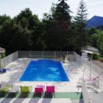 Piscine extérieure et transats dans un cadre de montagnes au Camping L'Amandier
