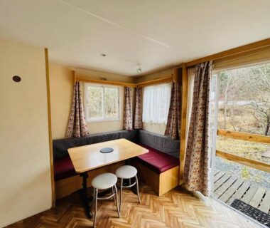Coin repas avec banquette table et tabourets dans mobil home du Camping L'Amandier