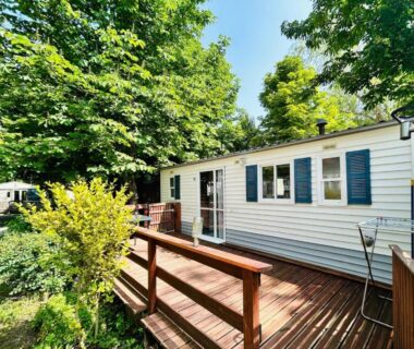 Terrasse en bois devant un mobil-home sous les arbres au Camping L'Amandier
