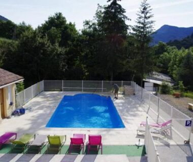 Piscine extérieure et transats dans un cadre de montagnes au Camping L'Amandier