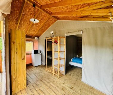 Intérieur de lodge en bois avec kitchenette et lit au Camping L'Amandier