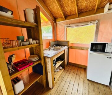Intérieur de tente avec coin cuisine et frigo au Camping L'Amandier