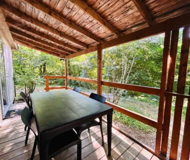 Terrasse couverte en bois avec table et chaises au camping L'Amandier