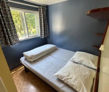 Chambre avec lit double et fenêtre au Camping L'Amandier