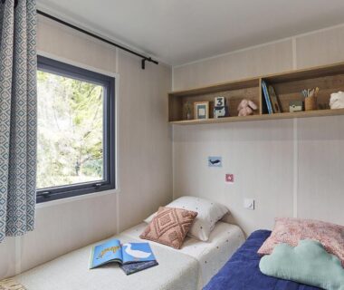 Chambre avec deux lits simples et fenêtre dans le locatif du Camping LE MOULIN DE CAUDON