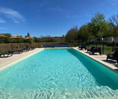 Piscine extérieure avec transats et ciel bleu au Camping LE MOULIN DE CAUDON