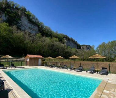 Piscine extérieure avec transats et parasols au Camping LE MOULIN DE CAUDON