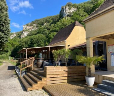 Terrasse en bois avec fauteuils et pots devant falaises au Camping LE MOULIN DE CAUDON