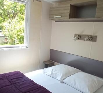 Chambre avec lit double et fenêtre au Camping LE Moulin