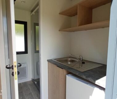 Intérieur kitchenette avec évier et salle d'eau dans le mobile home du Camping LE Moulin