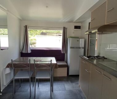 Intérieur de mobil-home avec kitchenette et coin repas au Camping LE Moulin