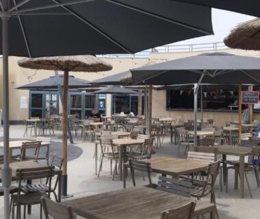 Terrasse extérieure avec tables et parasols au Camping LES DUNES Mobil home 6 personnes