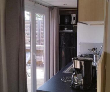 Intérieur avec cuisine et baie vitrée donnant sur terrasse du mobil home 6 personnes Camping LES DUNES