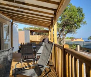 Terrasse en bois avec fauteuils et table et aperçu de la mer au Camping L'ILE D'OR