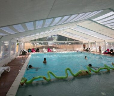 Piscine couverte avec baigneurs et transats au Camping La Belle Etoile