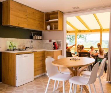 Intérieur kitchenette et coin repas ouvert sur terrasse du Camping La Chapoulière