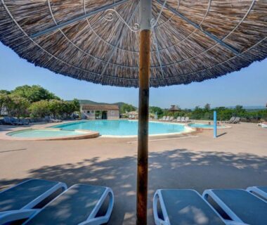 Bord de piscine avec transats et parasol au Camping La Chapoulière