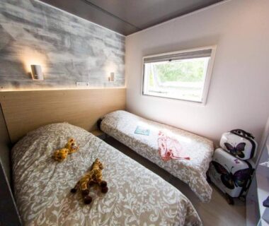 Chambre avec deux lits simples et fenêtre au Camping La Chapoulière