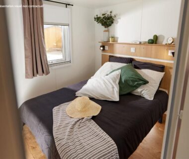 Intérieur chambre double avec lit et fenêtre au Camping La Chênaie