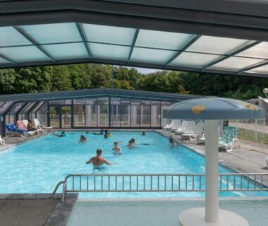 Piscine couverte avec parasol et baigneurs au Camping La Chênaie
