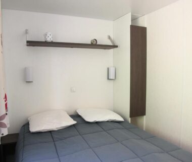 Chambre avec lit double et étagère dans le camping La Clé des Champs