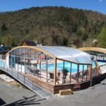 Piscine couverte avec toboggan et terrasse au Camping La Clé des Champs