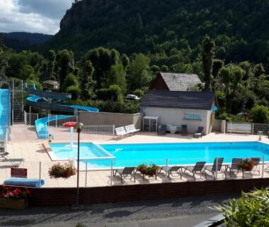 Piscine extérieure avec toboggan et chaises longues au Camping La Clé des Champs