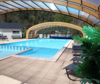 Piscine couverte avec transats et plantes au Camping La Clé des Champs