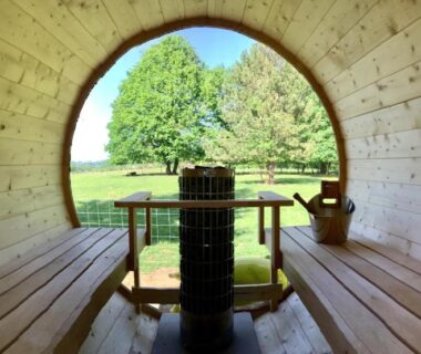 Sauna intérieur avec poêle et vue sur la pelouse du Camping La Ferme de Perdigat