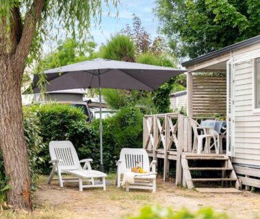 Terrasse de mobil-home avec transats et parasol au Camping La Forêt