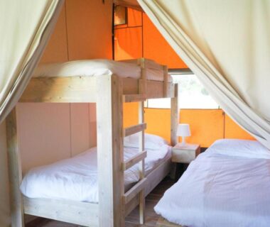 Intérieur de tente avec lits superposés et lit simple au Camping La Grappe Fleurie