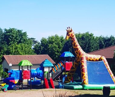 Aire de jeux avec structures gonflables et toboggan girafe au Camping La Grappe Fleurie