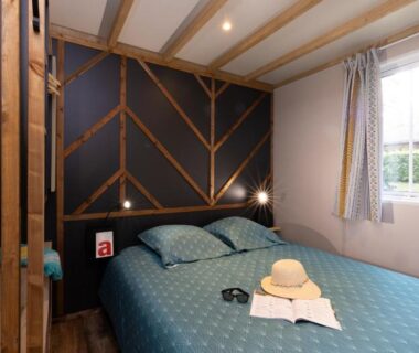 Chambre intérieure avec lit double et chapeau sur le lit du Camping La Grappe Fleurie