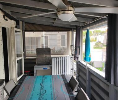 Terrasse couverte avec table turquoise chaises et ventilateur de plafond au Camping La Marine