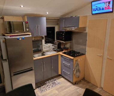 Coin cuisine avec réfrigérateur micro-ondes évier et plaque de cuisson dans l'hébergement du Camping La Marine