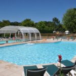 Piscine extérieure avec abris et transats au Camping La Mignardière