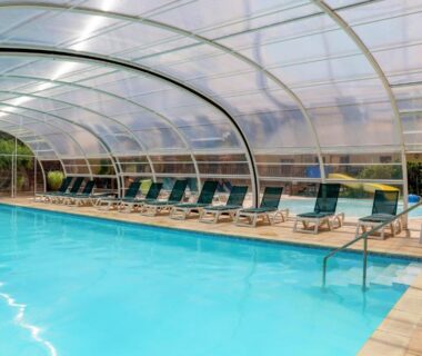 Piscine couverte avec rangée de transats au Camping La Mignardière