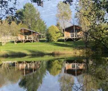 Bord d'étang avec chalets sur pilotis au Camping La Motte