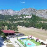 Piscine extérieure et aire de jeux au pied des montagnes au Camping La Pinatelle